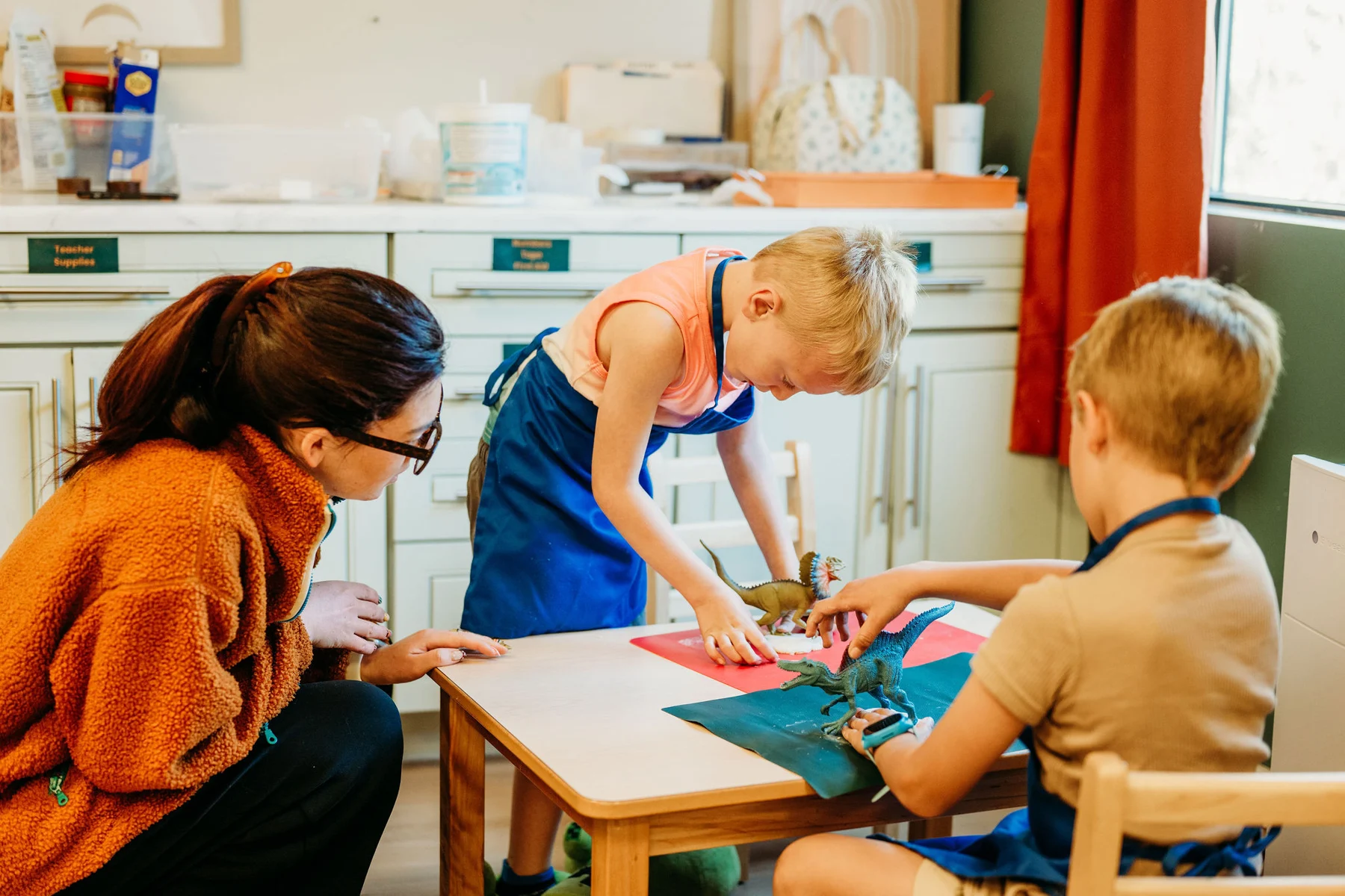 A Kindred Hill guide helping children explore clay at a classroom table