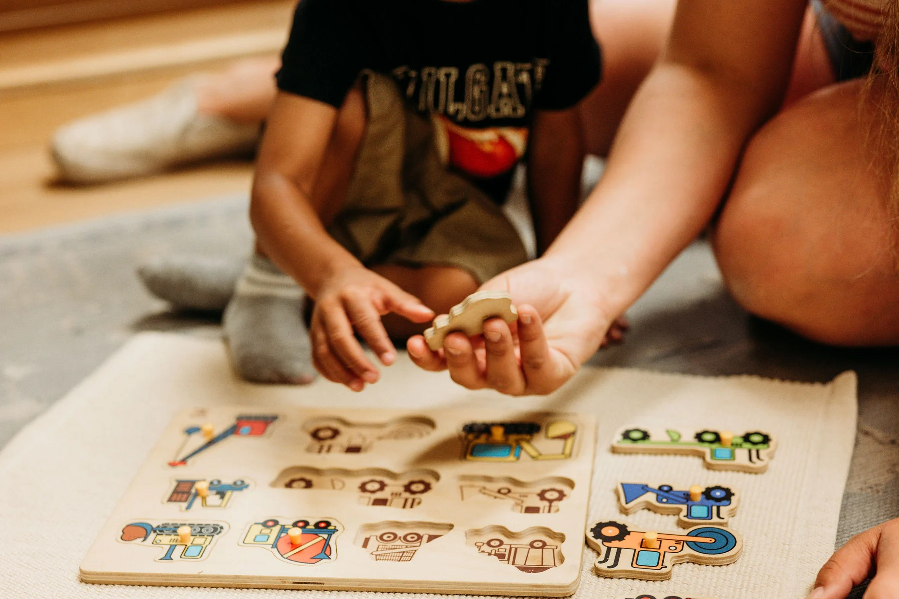 A Kindred Hill guide working alongside a child with a wooden puzzle