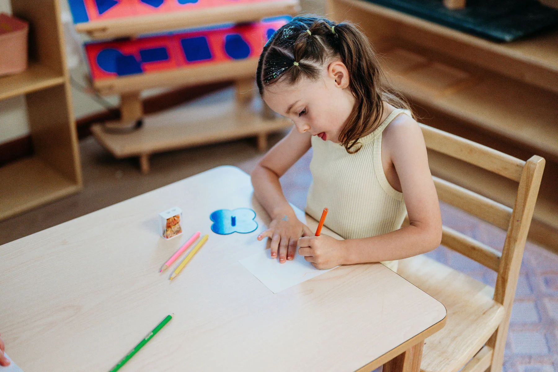 A child concentrating on a drawing at a Kindred Hill classroom table