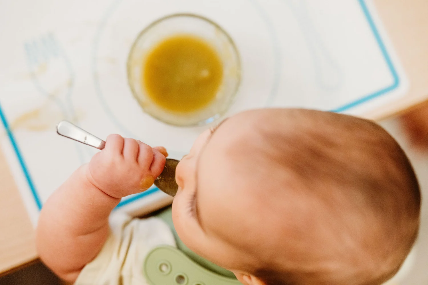 An infant practicing with a spoon during a meal at Kindred Hill